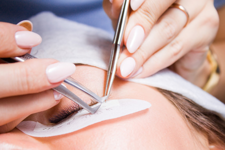 Beauty and fashion concept - Eyelash Extension Procedure. Woman Eye with Long false Eyelashes....