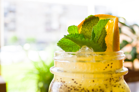 drinks, people and lifestyle concept - Fresh tropical yellow non-alcoholic cocktail in a mason jar decorated with slice of orange and peppermintの写真素材