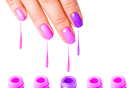 Beauty, fashion and Nail art concept - Woman hand close-up with five bottles of pink and purple gel nail polish and drops from fingers. isolated on white background. copy spaceの写真素材