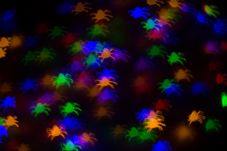 defocused bokeh multicolor lights in shape of spiders for halloween background - holidays,...