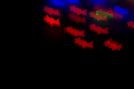 defocused bokeh multicolor lights in shape of bats for halloween background. copy space - holidays,...