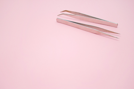 Beauty and fashion concept - tools for Eyelash Extension Procedure. Two tweezers on pink background. copyspace mockupの写真素材