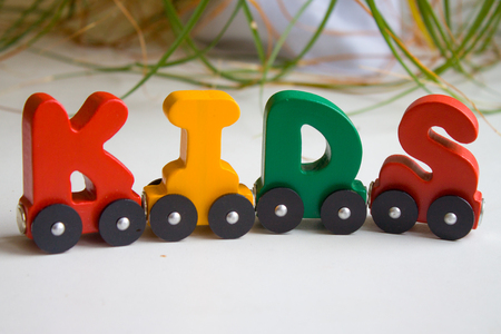 Word kids made of letters train alphabet. Bright colors of red yellow green and blue on a white background. Early childhood development, learning to read and kids game concept.の写真素材