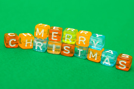 words merry christmas made of colorful blocks on green background. Flat lay, top view - holidays, winter, christmas and new year celebration conceptの写真素材