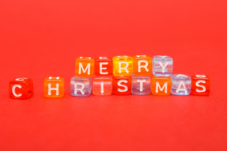 words merry christmas made of colorful blocks on red background. Flat lay, top view - holidays,...