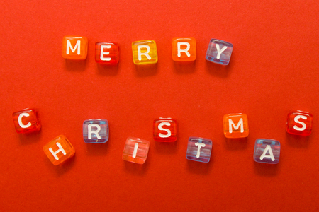 words merry christmas made of colorful blocks on red background. Flat lay, top view - holidays, winter, christmas and new year celebration conceptの写真素材