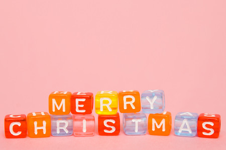 words merry christmas made of colorful blocks on pink background. Flat lay, top view - holidays,...