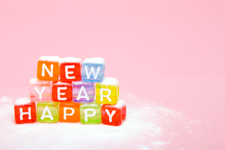 words happy new year made of colorful letters blocks on white snow and pink background. Flat lay, top view - holidays, winter, christmas and new year celebration conceptの写真素材