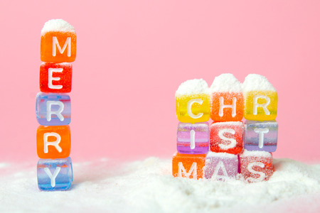 words merry christmas made of colorful letters blocks on white snow and pink background. Flat lay, top view - holidays, winter, christmas and new year celebration conceptの写真素材