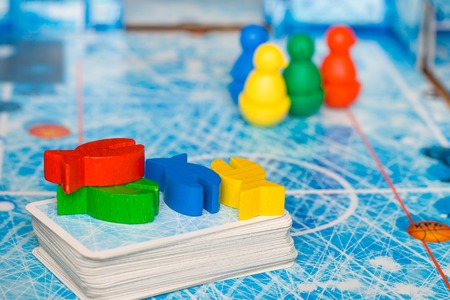 Board game and kids leisure concept - red, yellow, blue, green wood chips figure and playing cards in children playの写真素材