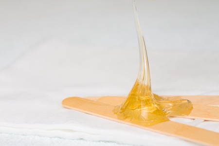 depilation and beauty concept - sugar paste or wax honey for hair removing with wooden waxing spatula sticksの写真素材