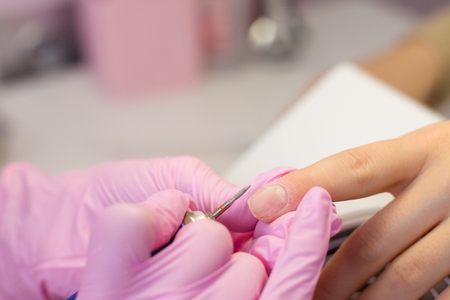 Hardware Manicure using electric device machine. procedure for the preparation of nails before applying nail polish. Hands of Manicurist in pink gloves and Nails of Client. Woman In Beauty Salon.の写真素材