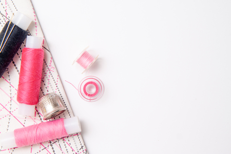 Multicolored thread coils on white background. Sewing supplies, thimble, pattern and accessories for needlework, stitching, embroidery. space for text. flat lay, top viewの写真素材