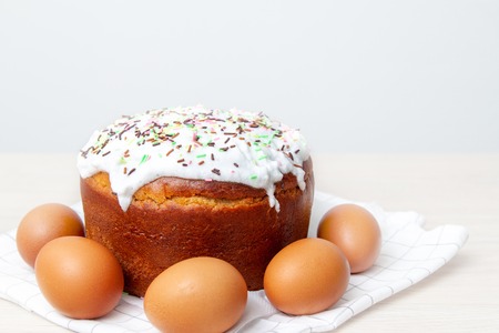 Easter cake and colored eggs on bright background. Holiday food and easter concept. Selective focus....