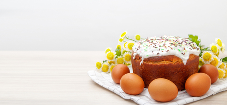 wide banner with Easter cake and colored eggs yellow flower blossoms on background. Holiday food and...
