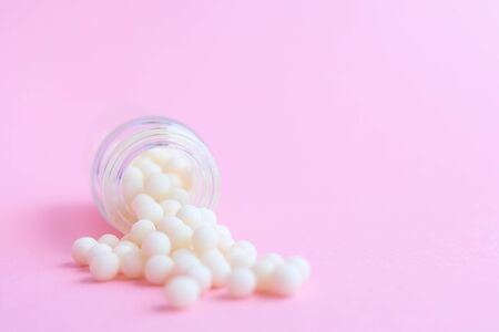 homeopathic globules and glass bottle close up on pink background. Alternative Homeopathy medicine herbs, healtcare and pills concept. Flatlay. copyspace for text.の写真素材