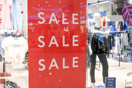 Season sale, black friday and shopping concept. Sale sign on red stand in shop store Clothes hangers and mannequins on background.- ST. PETERSBURG, RUSSIA - jul 17, 2019のeditorial素材
