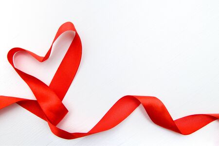 Heart shape made of red ribbon on white wooden Background. copy space Valentines and 8 March Mother Womens Day conceptの写真素材