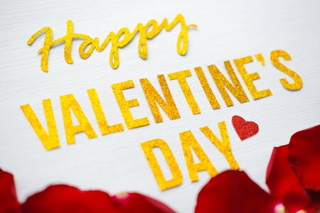 Happy Valentines Day text greeting card with red rose petals and heartson white wooden Background. romantic and Love concept.の写真素材