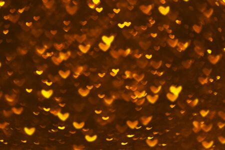 Valentines day abstract defocused gold bokeh background. Golden hearts bokeh lights on dark...