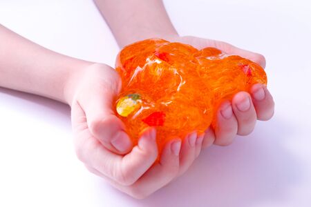 Orange round slime toy in kids hands on white background. Making slime. Copyspace. top view. Flatlay.の写真素材
