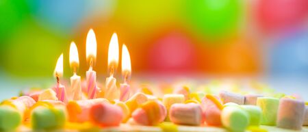 Festive colorful birthday banner with five burning candles on the cake and colorful balloons on background. Space for congratulatory text.の写真素材