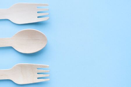 eco friendly disposable kitchenware utensils on blue background. wooden forks and spoons. ecology,...