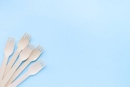 eco friendly disposable kitchenware utensils on blue background. wooden forks and spoons. ecology,...