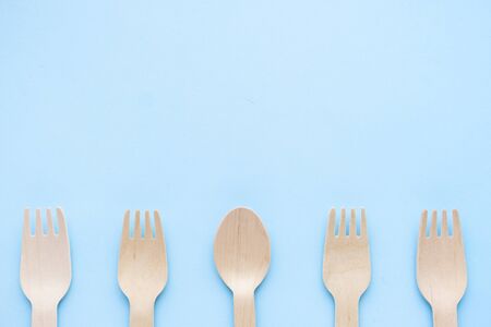 eco friendly disposable kitchenware utensils on blue background. wooden forks and spoons. ecology,...
