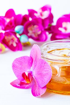 depilation and beauty concept - sugar paste or wax honey for hair removing with wooden waxing spatula sticks in jar on flower background. verticalの写真素材