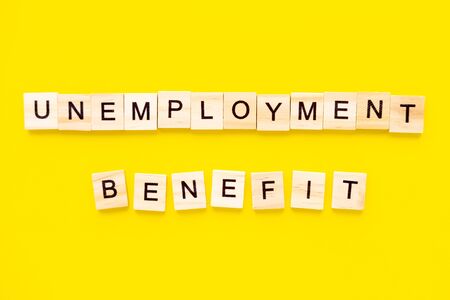 words unemployment benefit. Wooden blocks with lettering on top of yellow background. Human Resource Management and Recruitment and Hiring concept.の写真素材