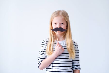 funny child blonde girl with mustache on grey background. Copyspace. Happy father dayの写真素材