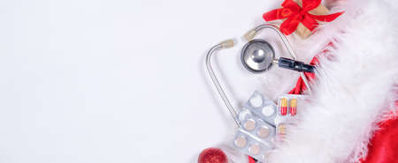 Medical Christmas card with pills, gift present box, stethoscope on white wooden background. Copyspace. Medicine new year flatly.の写真素材