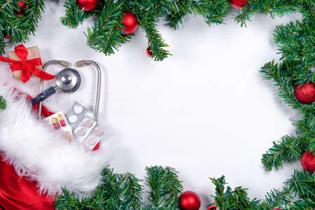 Medical banner with pills, gift present box, stethoscope and Christmas tree on white wooden background. Copyspace. Medicine new year flatly.の写真素材