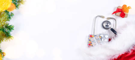 Medical banner with pills, gift present box, stethoscope and Christmas tree on white wooden background. Copyspace. Medicine new year flatly.の写真素材