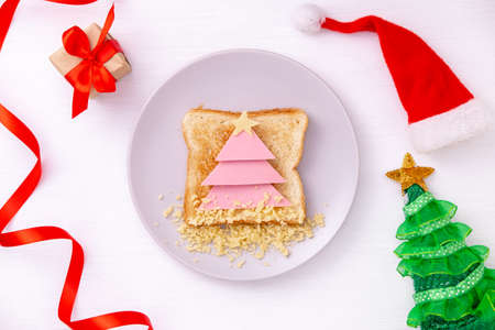 Funny sandwich with edible Christmas tree made from toast bread, sausage and cheese. Breakfast idea for kids. New Year food background top view . holiday, celebration, food art conceptの写真素材