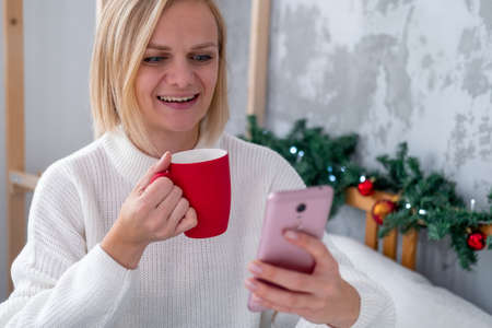 Christmas online shopping. Female buyer makes order on laptop. Woman buy presents, prepare to xmas, among gift boxes and packages. Winter holidays salesの写真素材