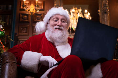 Kids and Santa in medical masks. Girl and Santa Claus reading Christmas book sitting near Christmas...