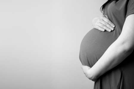 healthy pregnancy. side view pregnant woman with big belly advanced pregnancy in hands. Banner copyspace for text. Stylish Black and white photo.の写真素材