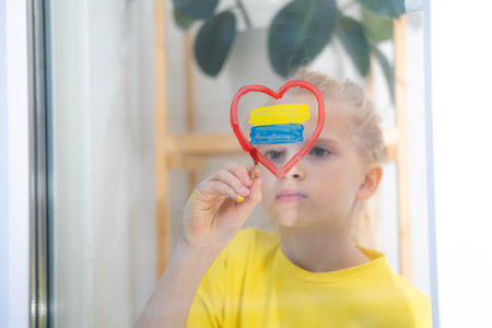 Girl painting flag of Ukraine on the window upset and survives the war Ukraine Russiaの写真素材