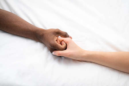 Hands close up multiracial couple african man and caucasian woman romantically touch each other...