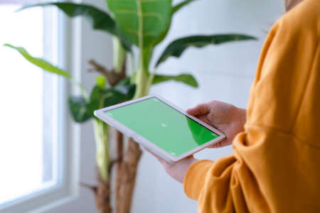 Girl using iPad tablet viewing green screen press browsing chroma key online typing text reading...