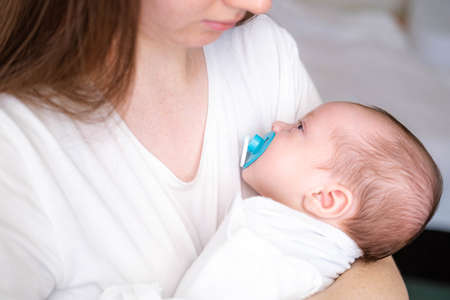 Portrait newborn baby boy lying in nursery cocoon with blue clothes on bed in bedroom at home, happy baby morningの写真素材