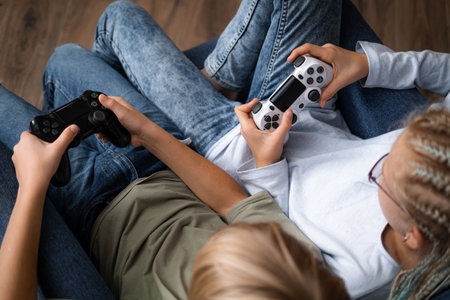 boy and girl playing video game console using joystick or controller while sitting at home, Two...