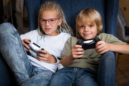 boy and girl playing video game console using joystick or controller while sitting at home, Two...