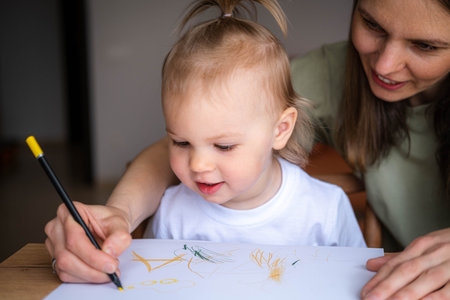 mother teach daughter girl paint or writing use album and colourful pencils at home in sunny cozy living room, Educational pastime develop creativity skill in kidの写真素材