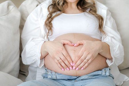 Mother love. pregnant woman with big belly advanced pregnancy resting sitting on sofa at home making...