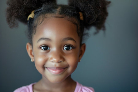 portrait black little girl, joyful childs beaming smile, playful hair puffballs, portrait of happiness, childrens apparel and lifestyle conceptの素材