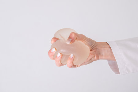 doctor squeezes in his hand breast enlargement implant, plastic surgery, beauty enhancement, medical Mammoplasty and plastic surgery, mastopexyの写真素材