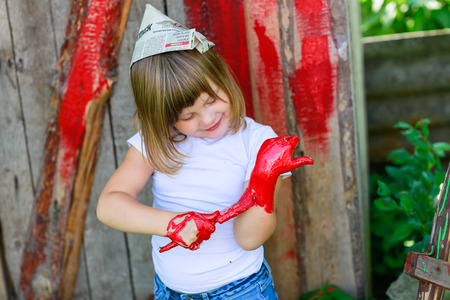 Girl with a brush with red paint, paint the outside barnの写真素材